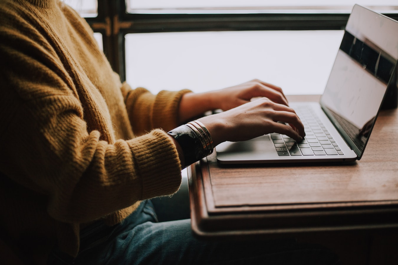 A professional typing an email on a laptop at a clean desk