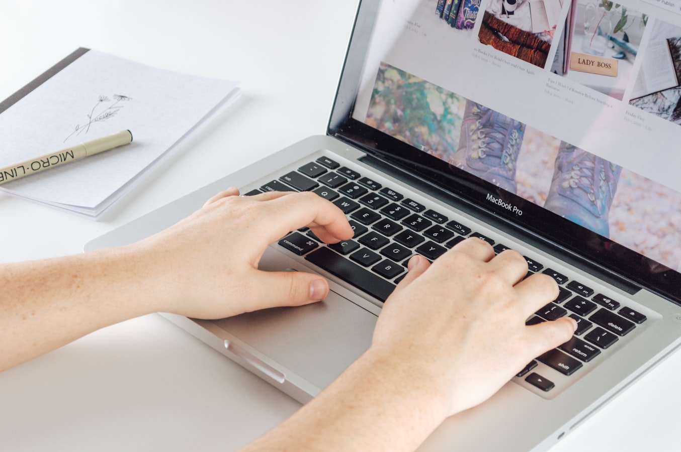 A person adjusting a print template on a laptop screen beside a stack of printed brochures