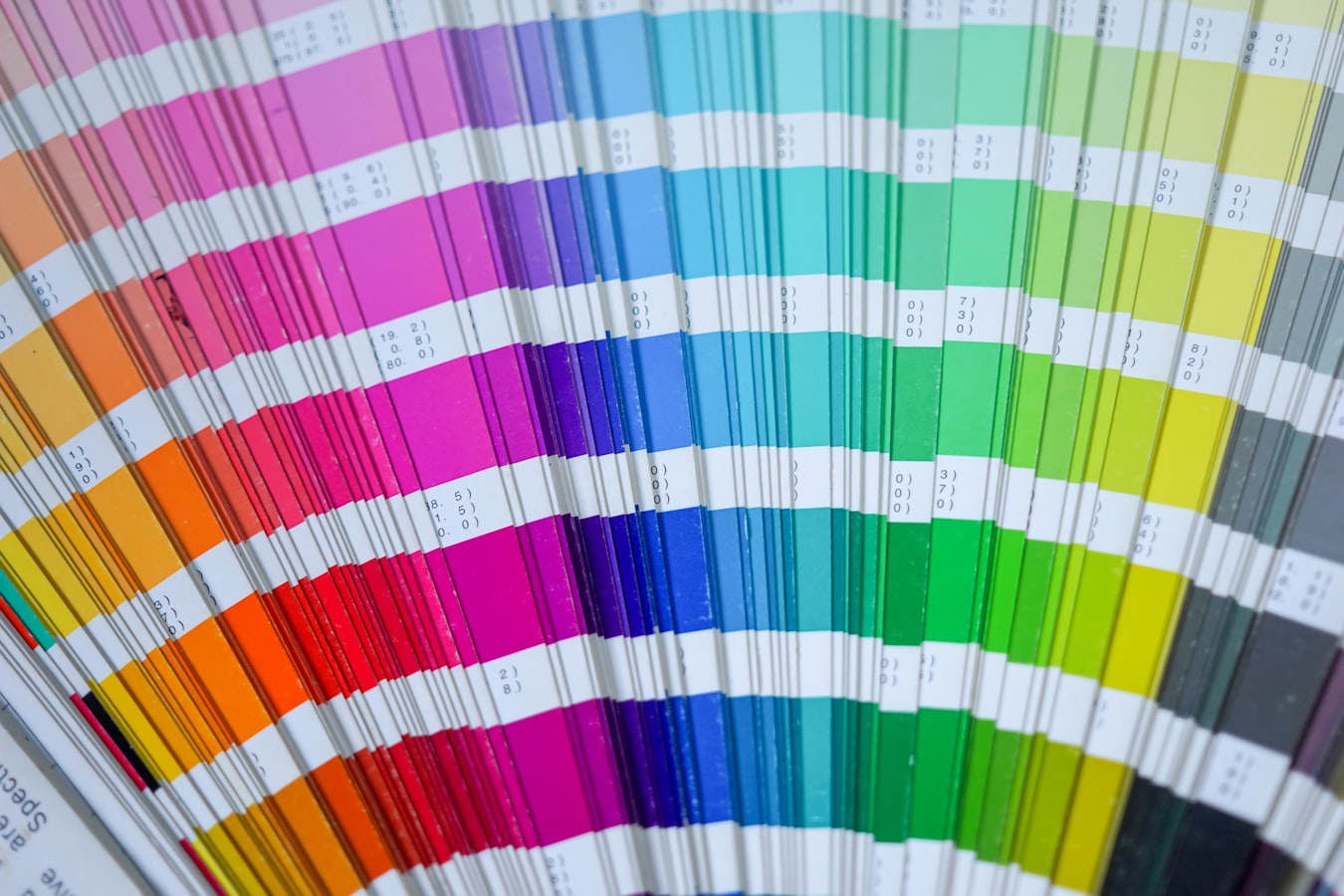 Stacks of CMYK-printed sheets coming off a commercial printing press