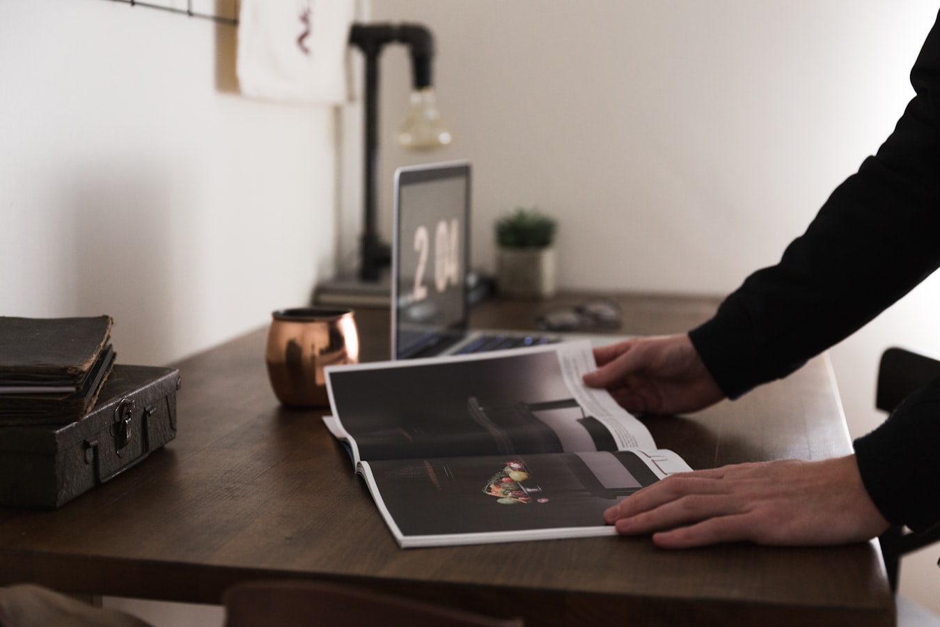 A designer at a desk reviewing multiple printed layout sheets for different clients