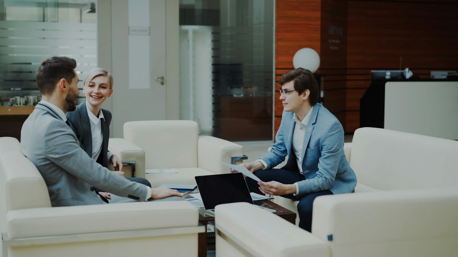 Two executives sharing contact details on a smartphone in a modern office setting
