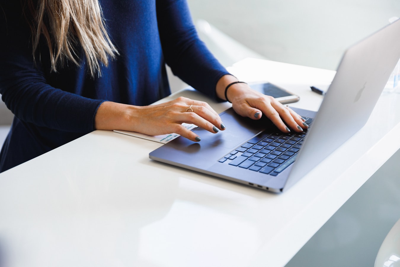 A person composing an email on a laptop at a tidy desk
