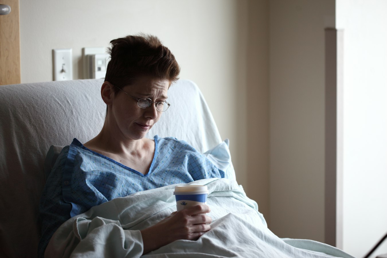 A nurse glances at her phone with a calm, professional expression in a bright clinical hallway