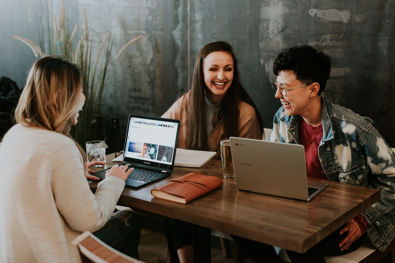 A small professional team gathered around a table, each holding their phones while exchanging contact information.