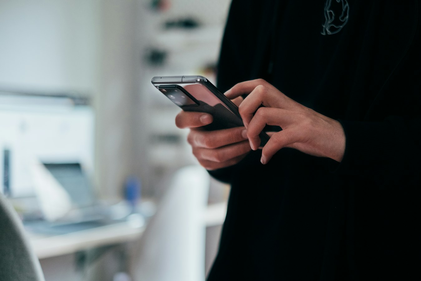 A person holding a smartphone and showing their screen to someone nearby