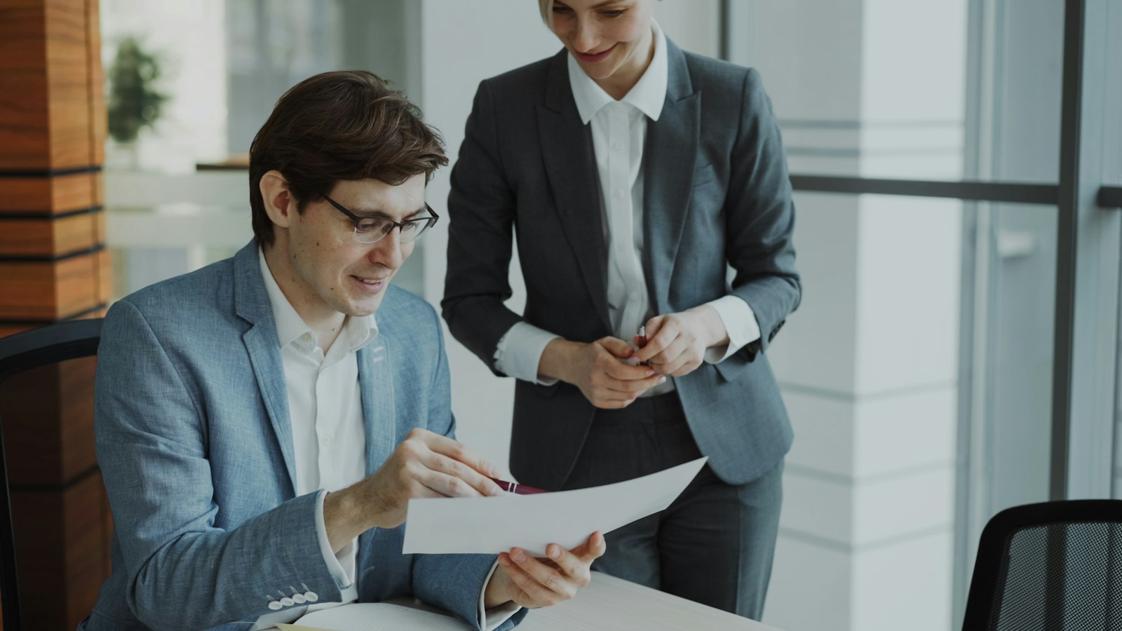 Two people sitting at a table reviewing a printed agreement together