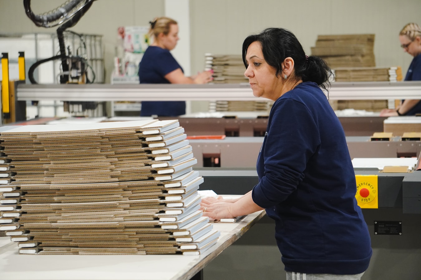 A print shop worker reviewing a stack of printed proofs at a production table