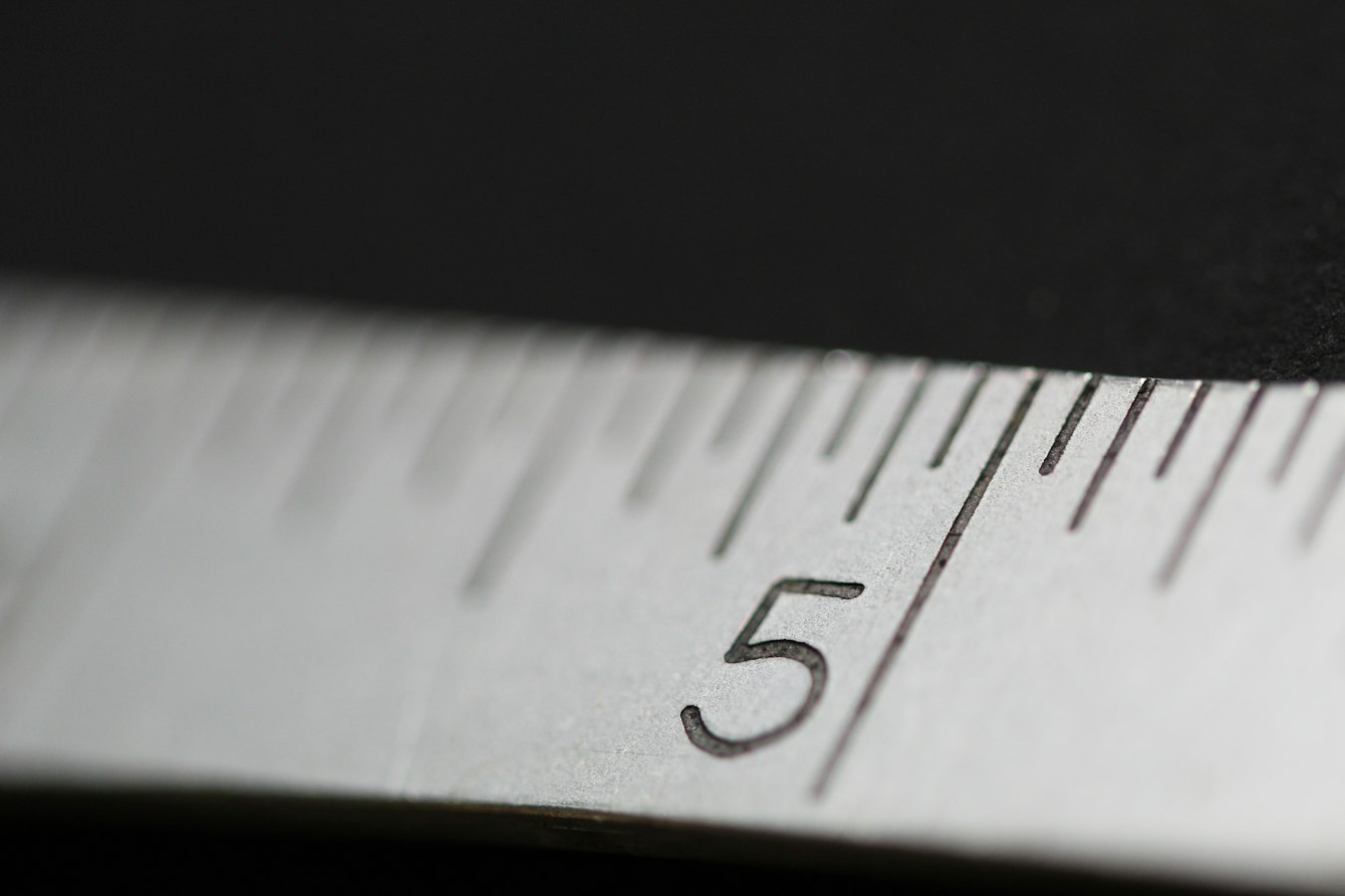 A metal ruler laid across a printed document on a desk, showing precise measurements
