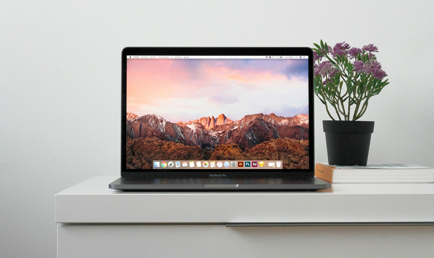 A MacBook on a clean desk showing a Word document open on screen