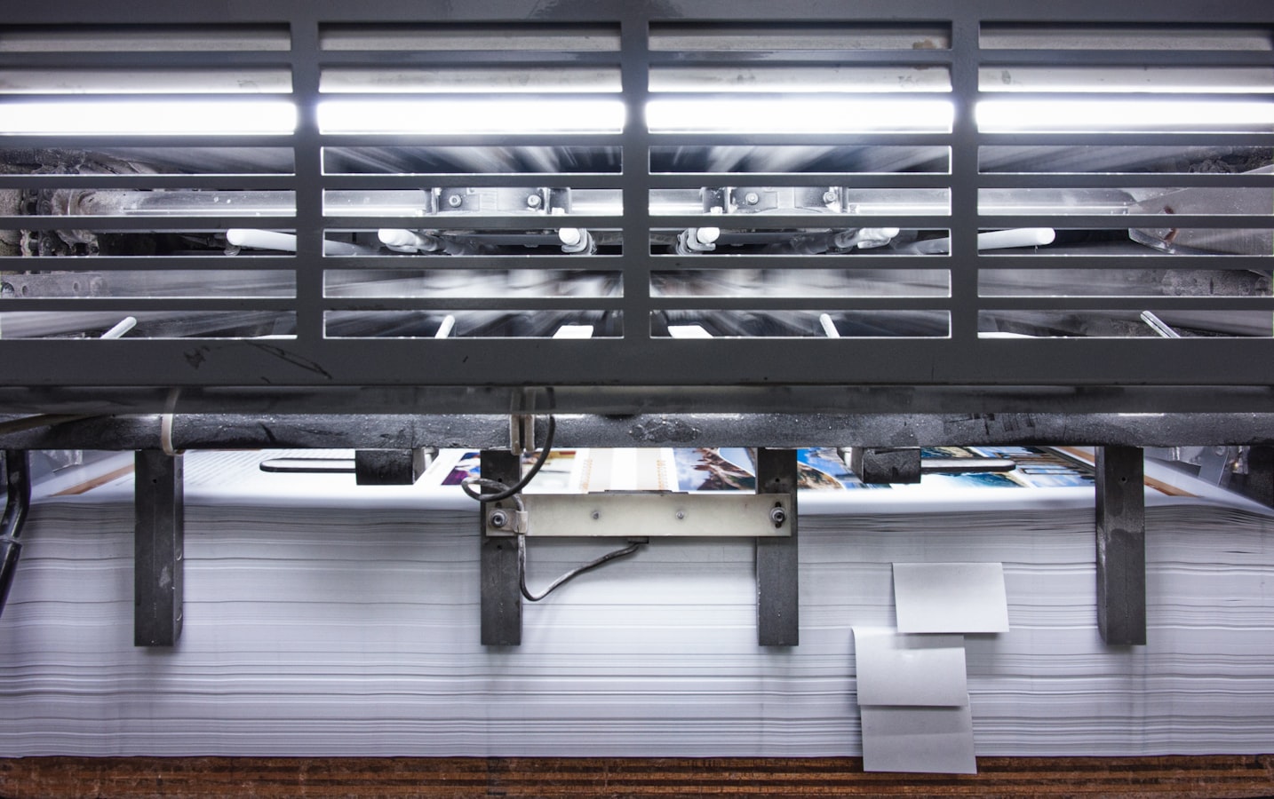 A print shop operator examining a freshly printed sheet for color and registration errors