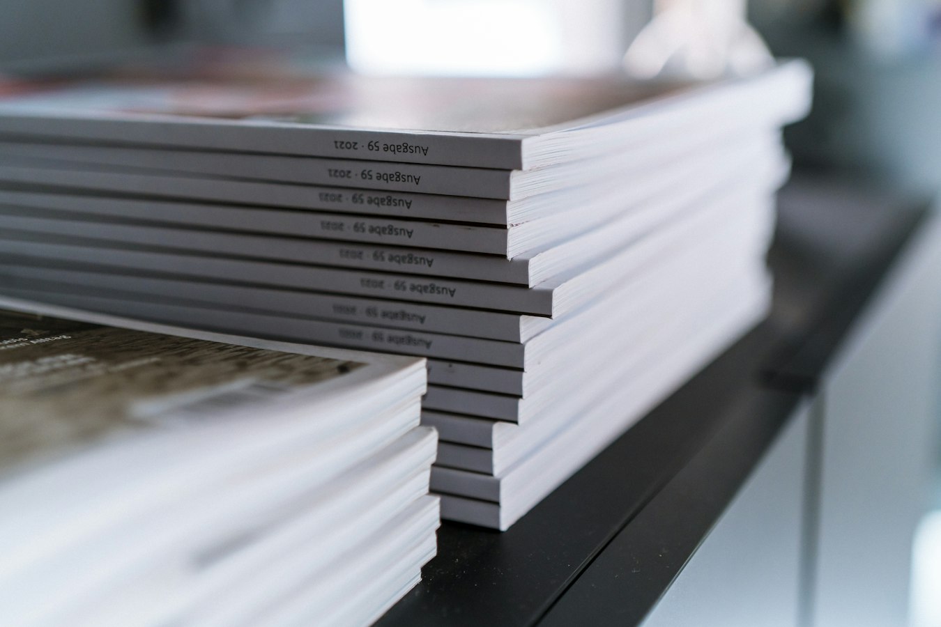 Neatly stacked printed brochures ready for repeat production runs on a print shop workbench