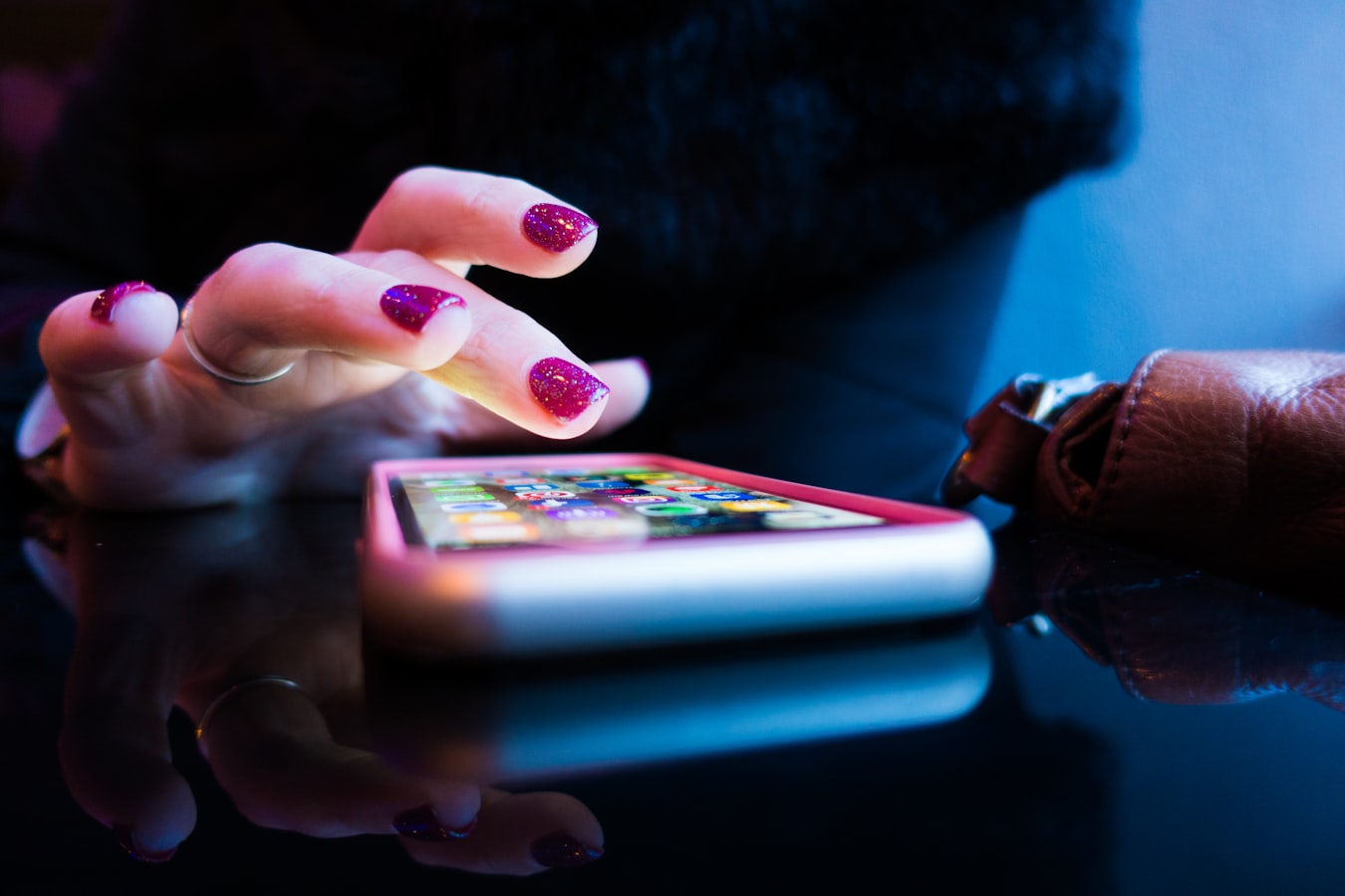 A person tapping a smartphone to a small white NFC tag on a wooden desk