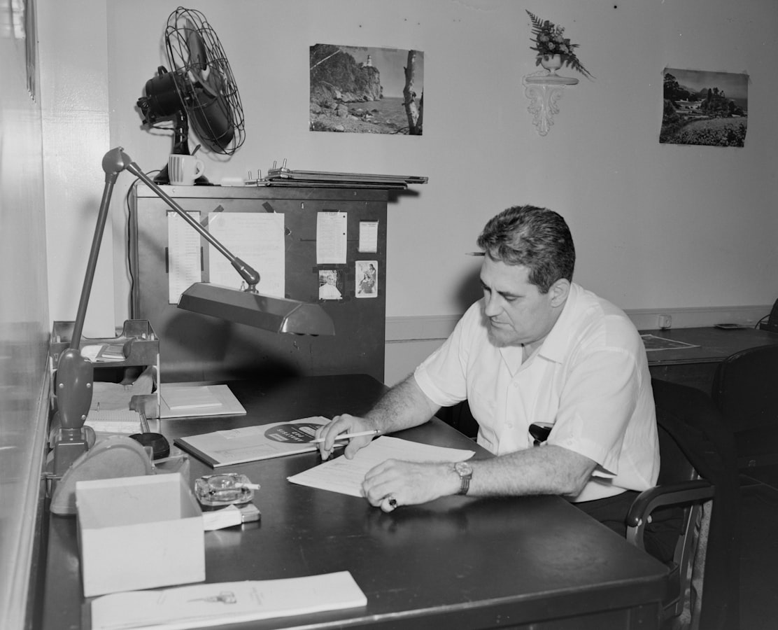 Print shop worker reviewing a physical proof sheet at a production desk