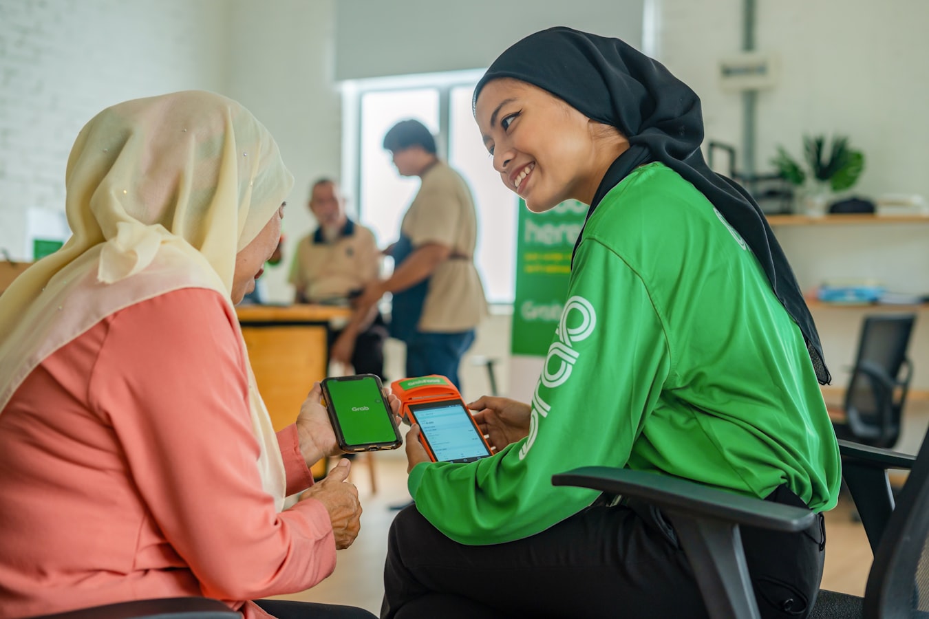 Two nonprofit volunteers smiling and sharing contact information on a smartphone outdoors