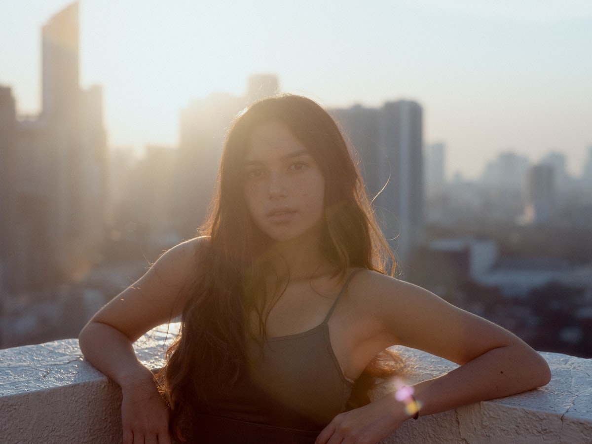 Photographer setting up a camera on a city rooftop with buildings in the background
