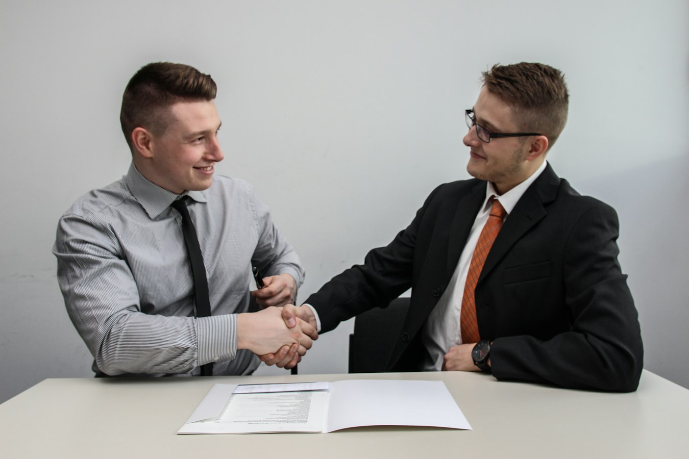 An insurance agent and client sitting together at a desk, reviewing documents and smiling