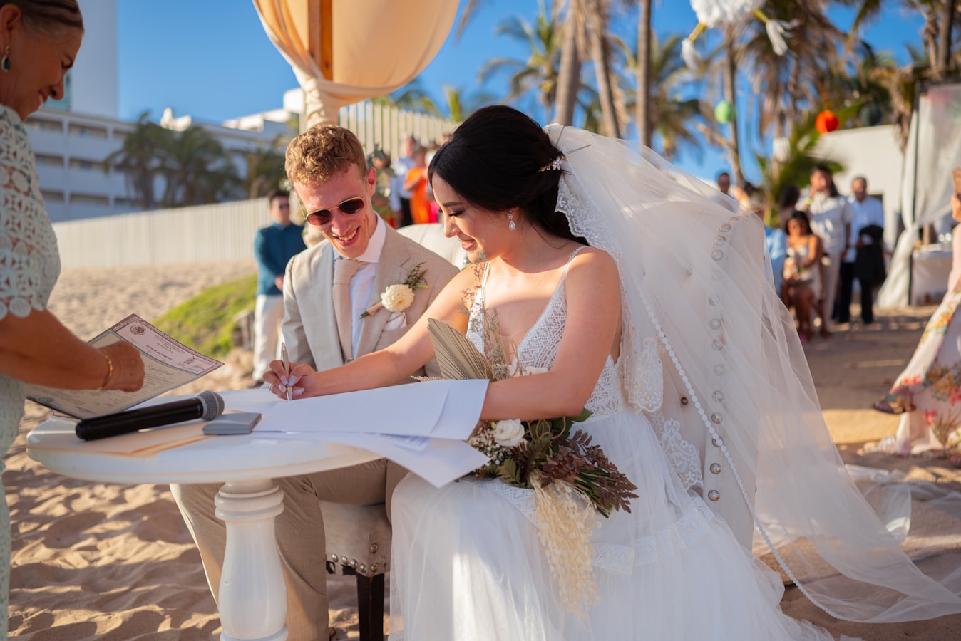 A couple signing a document at their wedding venue with a photographer nearby