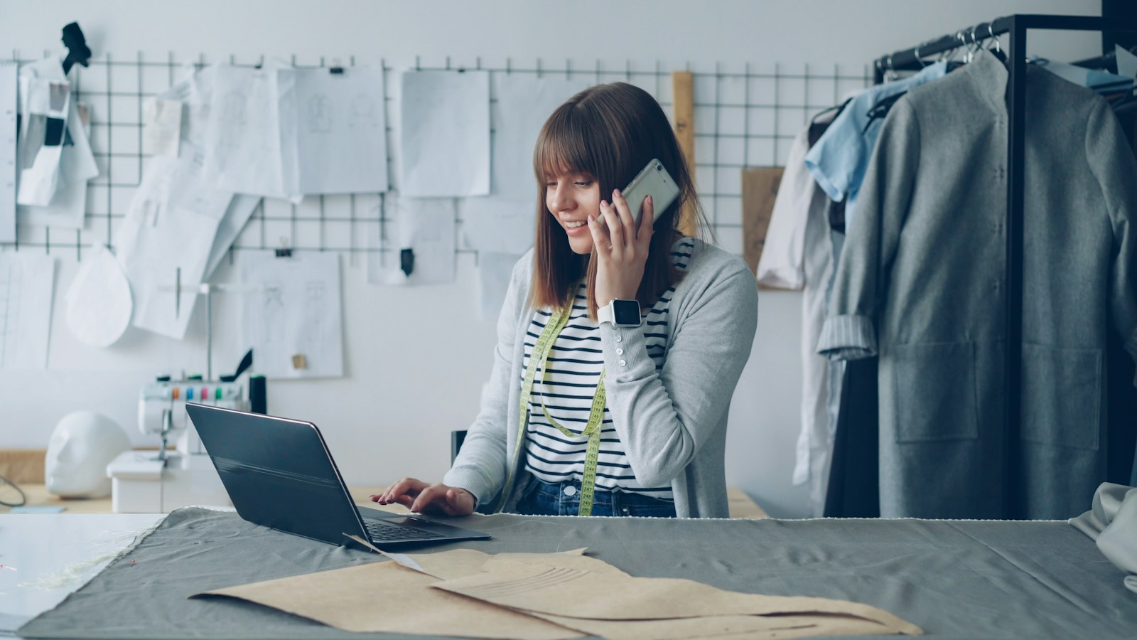 A small business owner smiling while looking at their phone in a cozy shop setting