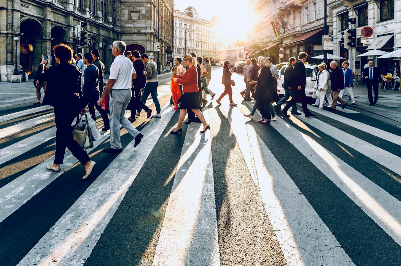 Pedestrians walking along a busy urban sidewalk, shot from street level by a photographer