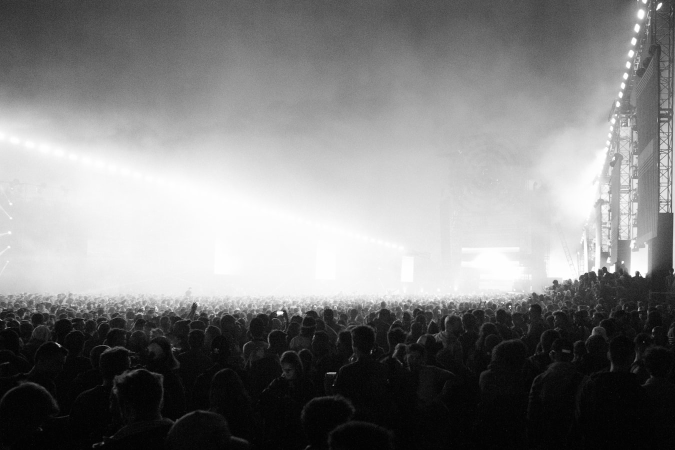 A photographer shooting a live concert from the crowd with stage lights overhead