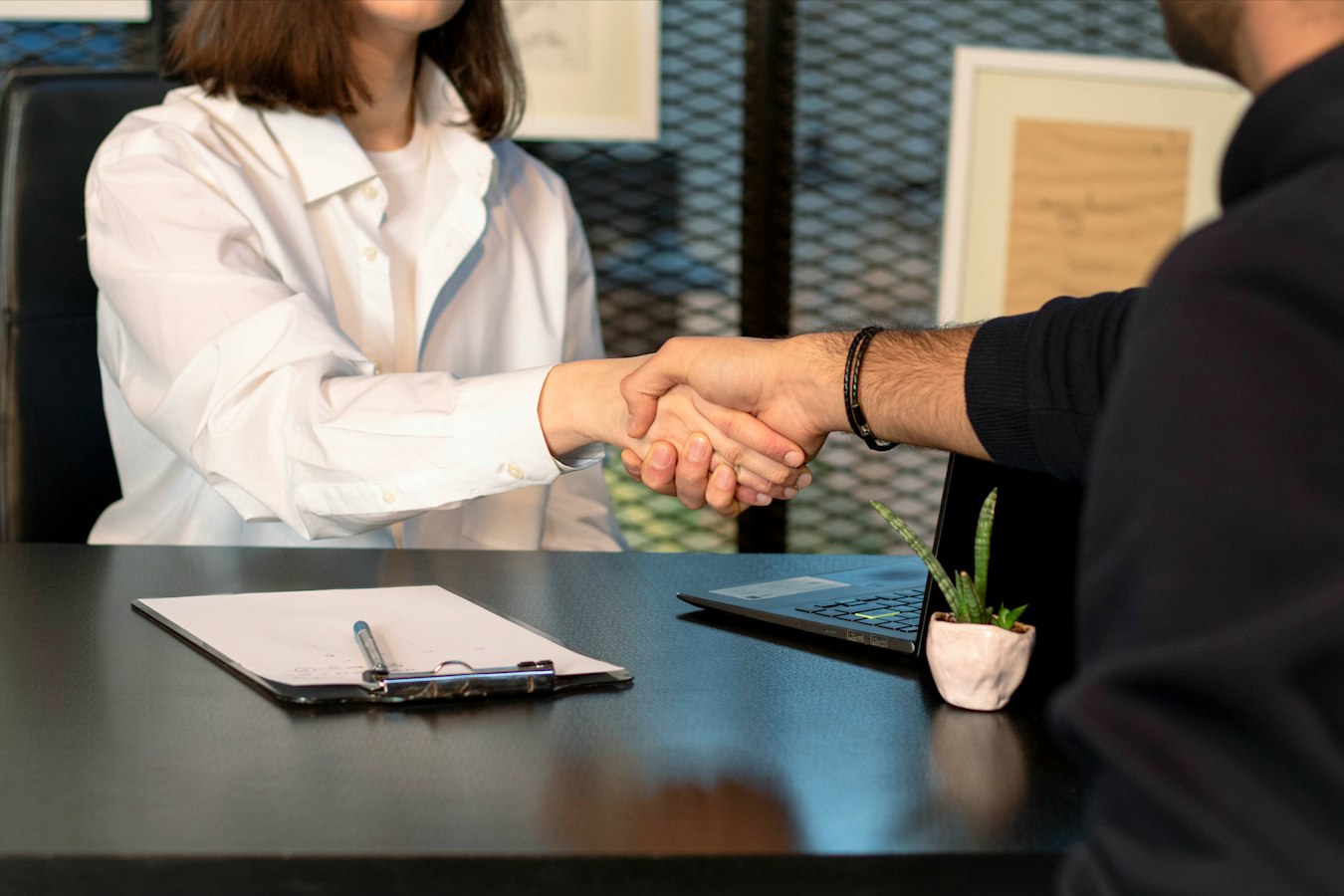 Two professionals shaking hands and exchanging contact details at a trade show booth