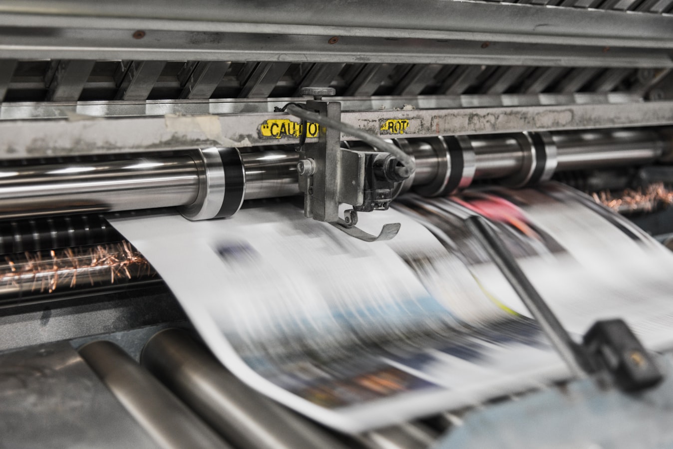 A print shop worker reviewing printed sheets at a production press