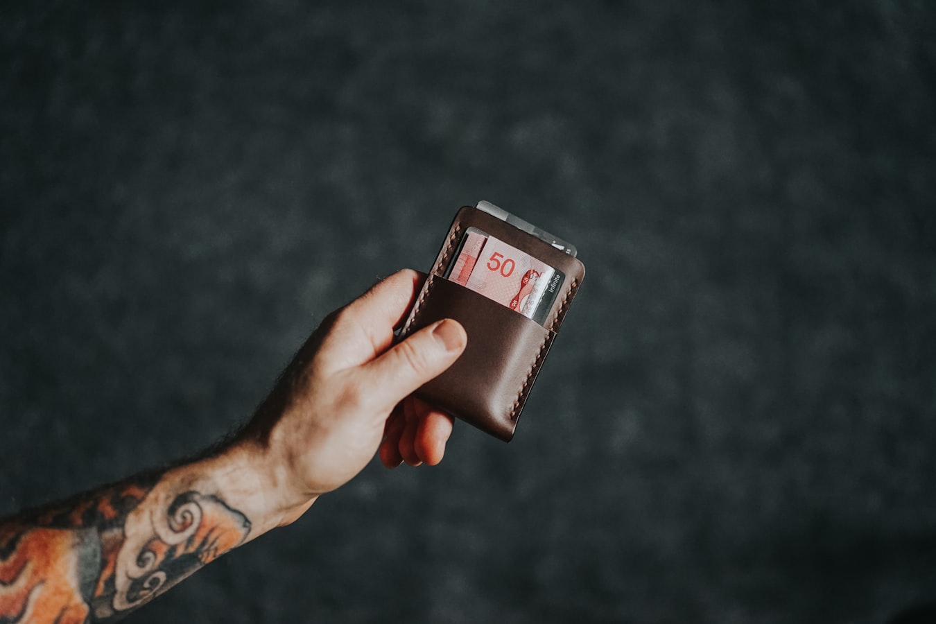 A person holding an iPhone displaying the Wallet app with a card on screen