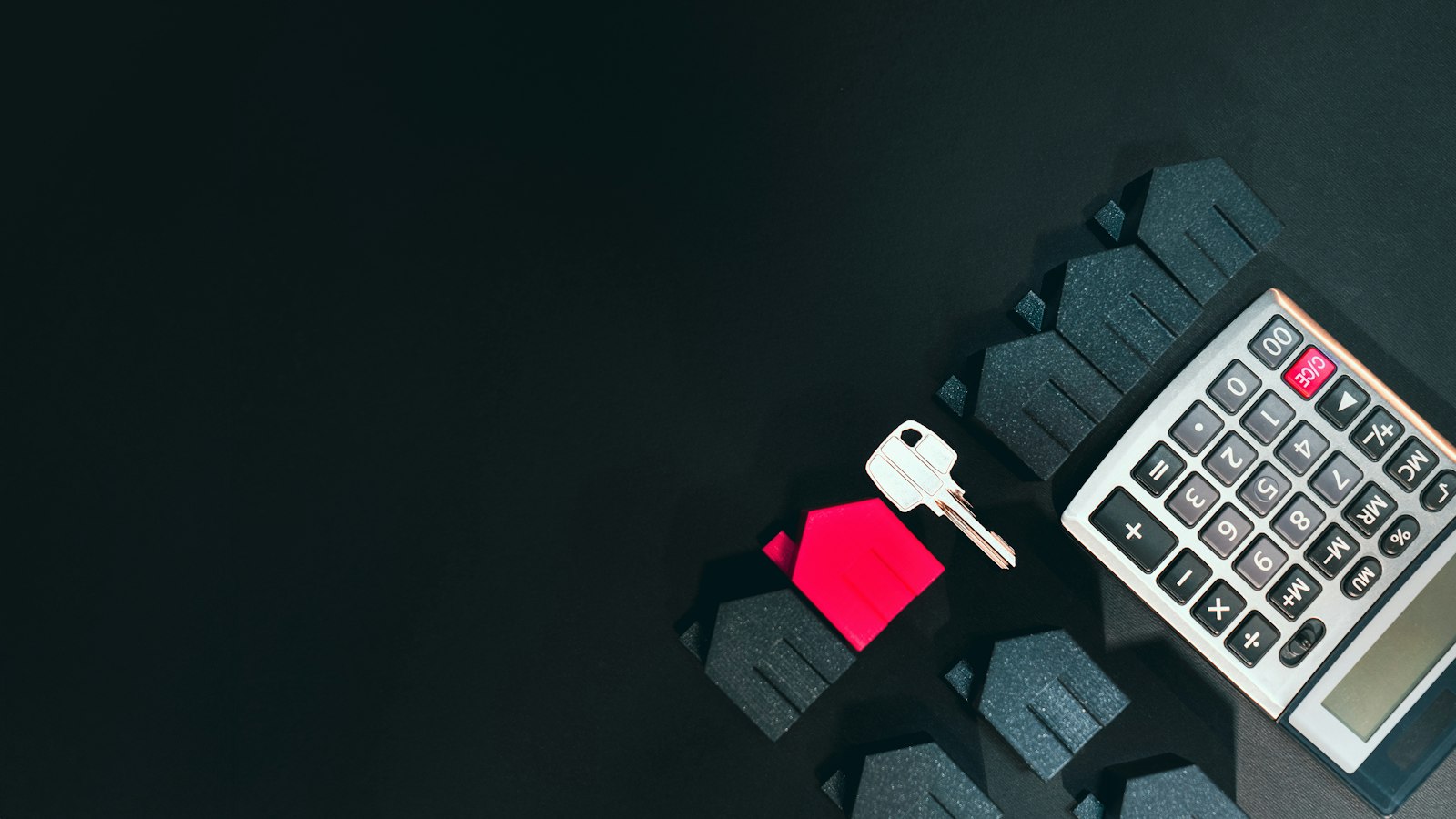 A stack of insurance documents next to a set of house keys on a wooden desk