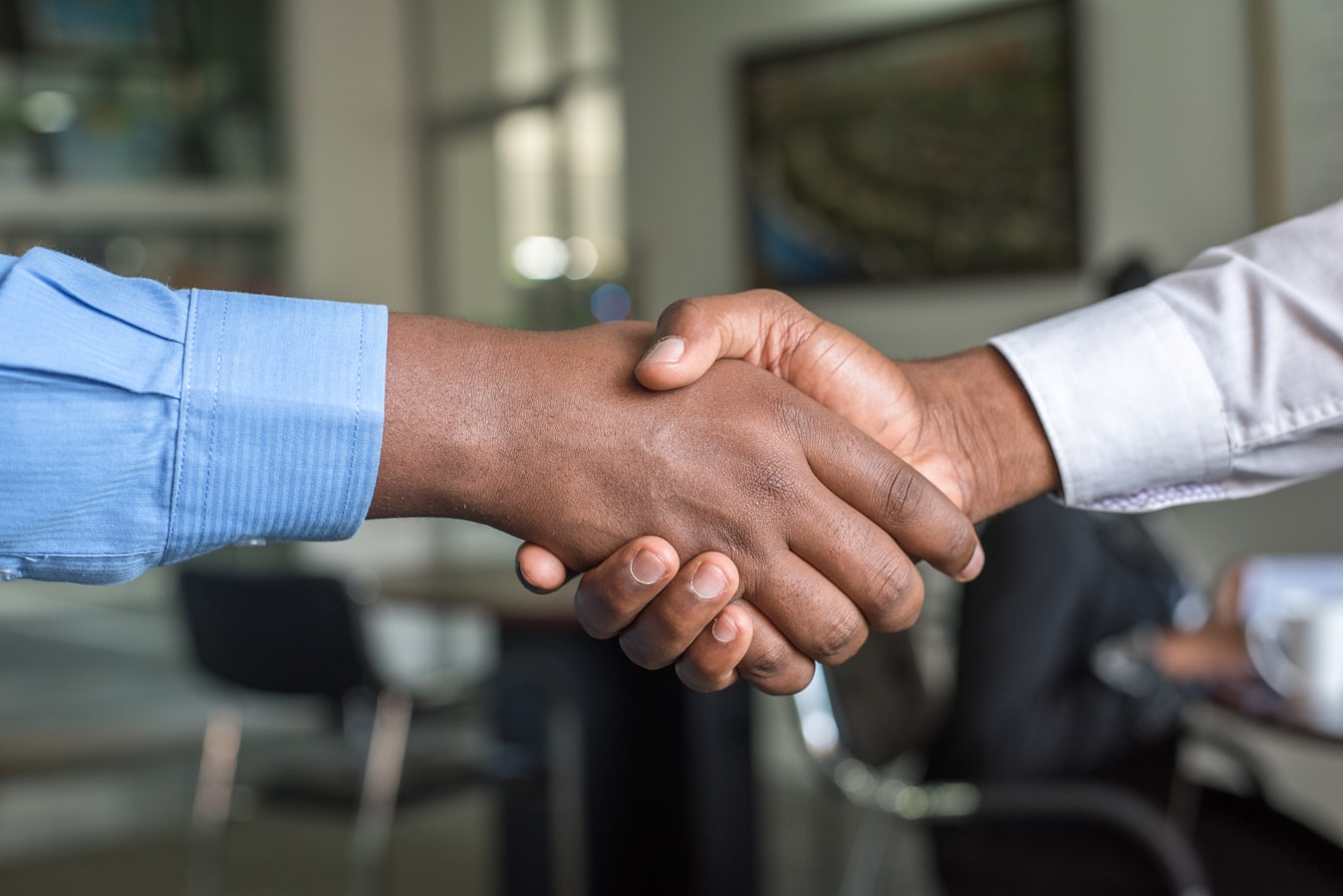 A lawyer shaking hands with a client across a desk in a professional office setting